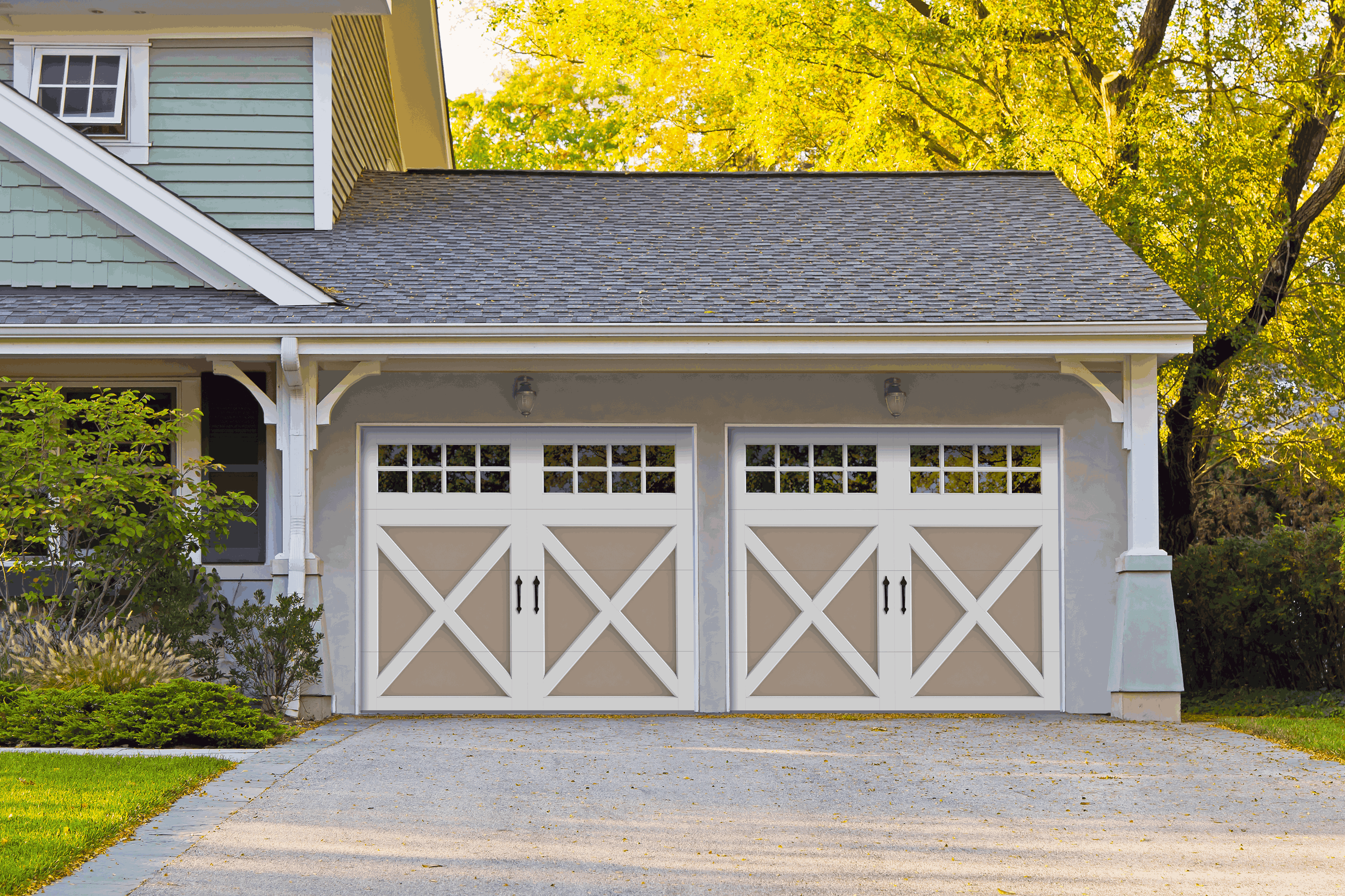 A two-story home that has two carriage-style garage doors with a beige base, white accents, and square windows.